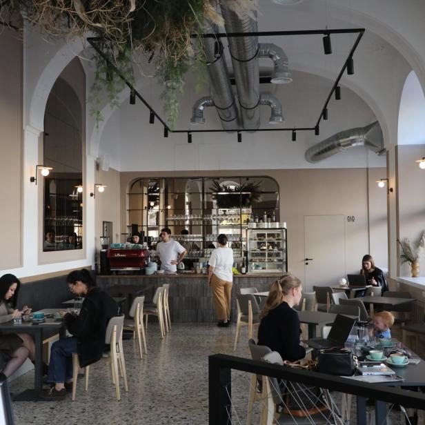 Innenansicht eines Cafés mit mehreren Gästen an Tischen.