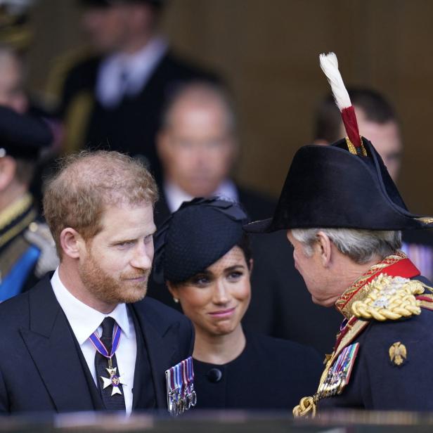 Prinz Harry und Meghan in einem Gespräch mit einem Mann in Uniform.