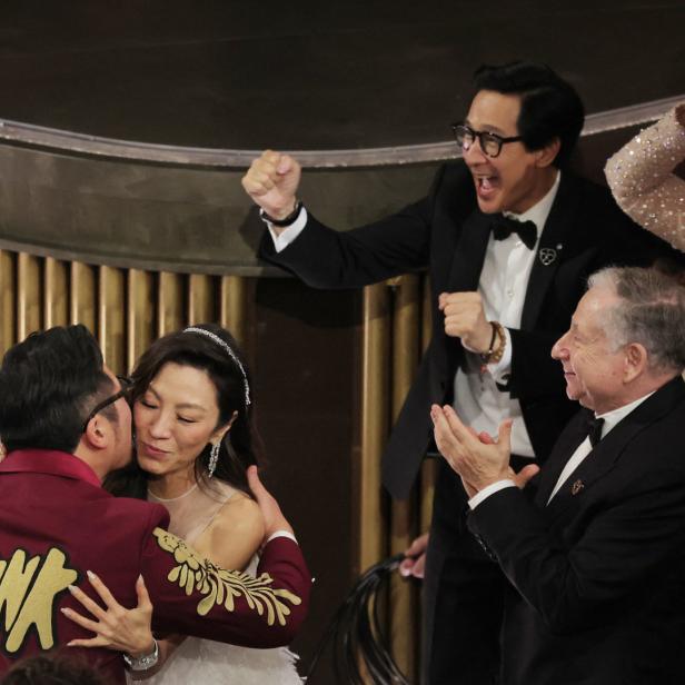 Michelle Yeoh wird nach ihrem Oscar-Gewinn umarmt, während andere applaudieren und jubeln.