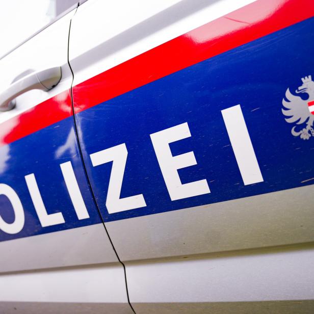 Der Schriftzug „Polizei“ und das österreichische Wappen auf einem Polizeiauto.