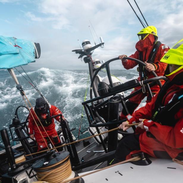 Segler in roter Schutzkleidung steuern ein Segelboot während des Ocean Race 2023.