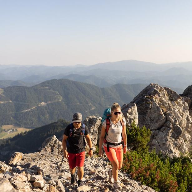 Zwei Wanderer auf einem Berg mit einer beeindruckenden Berglandschaft im Hintergrund.