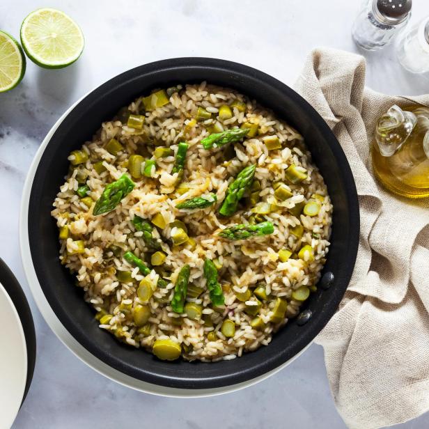 Risotto mit Spargel in einer Pfanne auf einem weißen Marmortisch. von oben aufgenommen. vegane und vegetarische gesunde italienische Küche.