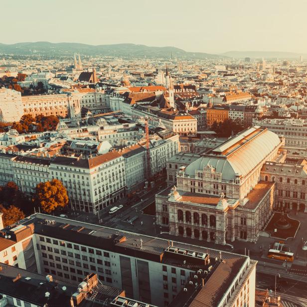 Luftaufnahme der Wiener Staatsoper und der umliegenden Stadtlandschaft bei Sonnenaufgang.