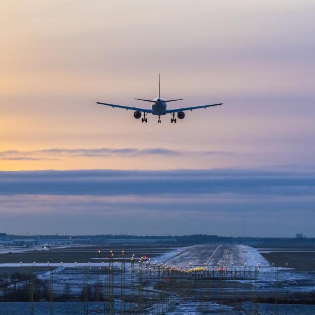 Ein Flugzeug landet auf der Landebahn eines Flughafens bei Sonnenuntergang.