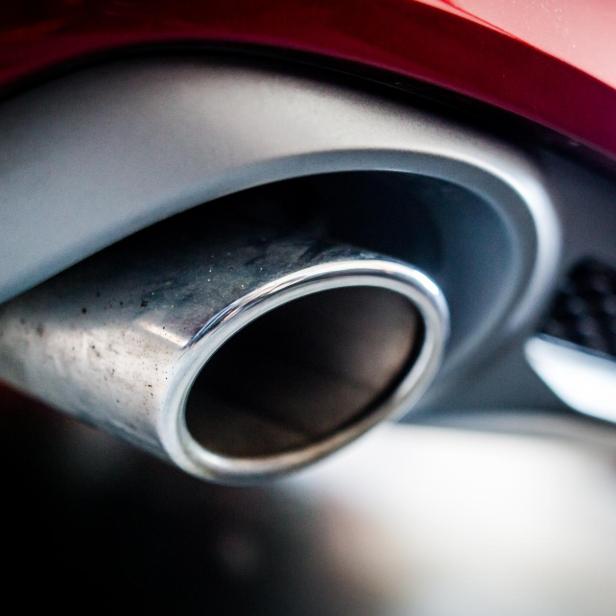 Ein verchromtes Auspuffrohr an einem roten Auto.