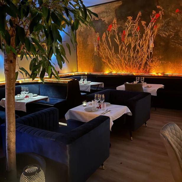 Ein elegant eingerichtetes Restaurant mit blauen Samtsesseln und einem Wandgemälde.