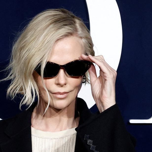 Charlize Theron posiert mit Sonnenbrille auf einem Event.