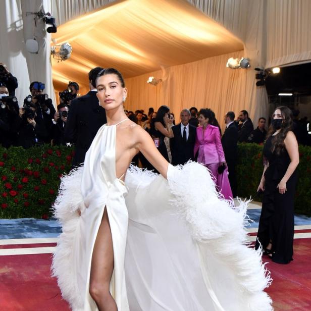 Hailey Bieber in einem weißen Kleid mit Federn auf dem roten Teppich.