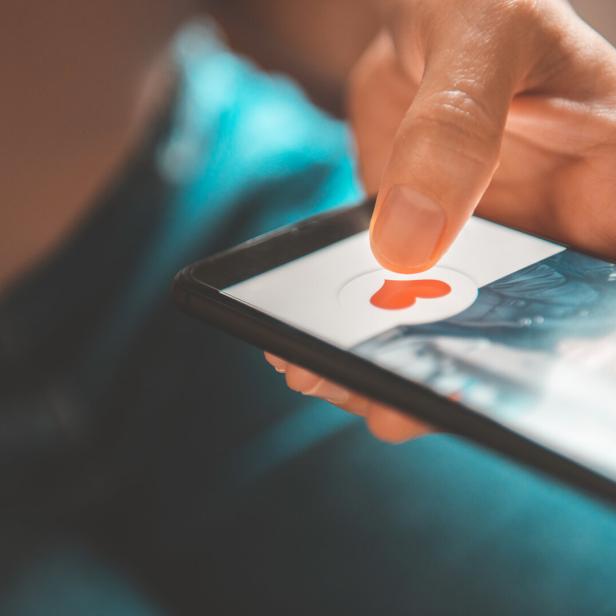 Eine Person tippt auf einem Smartphone auf ein Herz-Symbol.