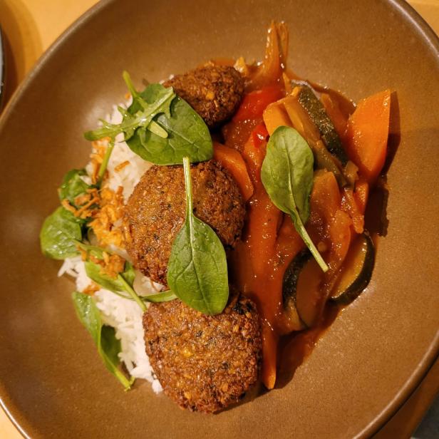 Eine Schüssel mit Falafel, Reis und geschmortem Gemüse wird serviert.