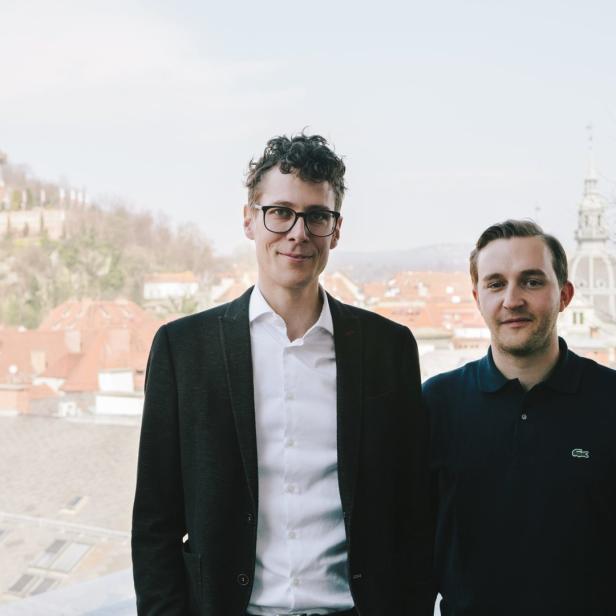 Zwei Männer posieren vor der Skyline von Graz, Österreich.
