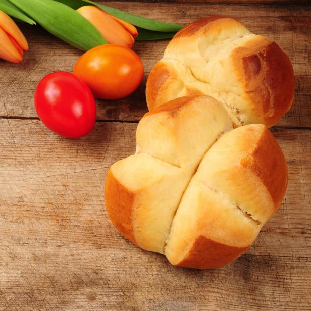Tulpen, gefärbte Eier und Osterbrot liegen auf einem Holztisch.