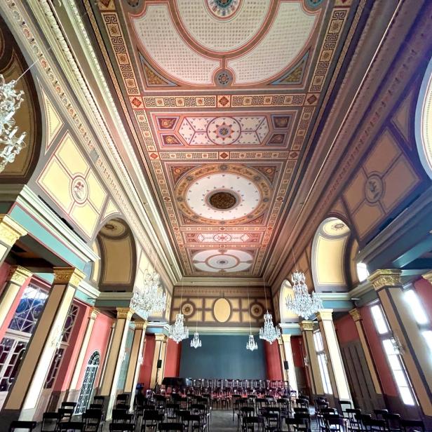 Ein prunkvoller Saal mit Kronleuchtern und einer reich verzierten Decke.