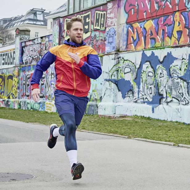 Ein Mann joggt vor einer Wand mit Graffiti.