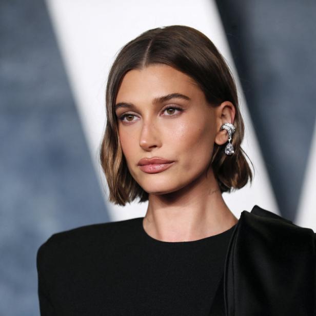 Hailey Bieber mit kurzem, gewelltem Haar und einem auffälligen Ohrring.
