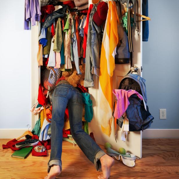 Eine Person klettert in einen überfüllten Kleiderschrank.