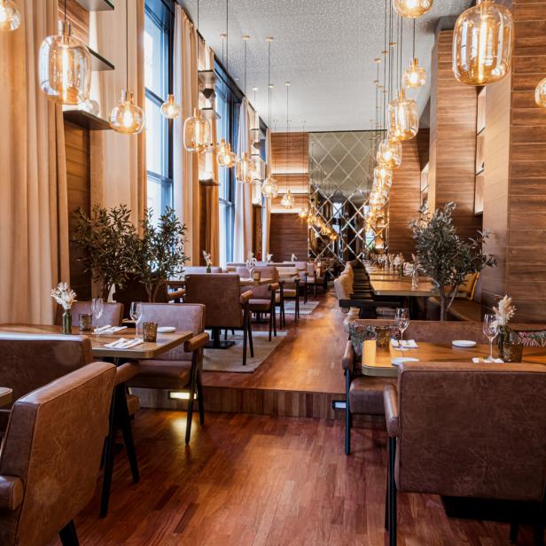 Ein elegantes Restaurant mit Holzböden, braunen Ledersesseln und dekorativen Lampen.