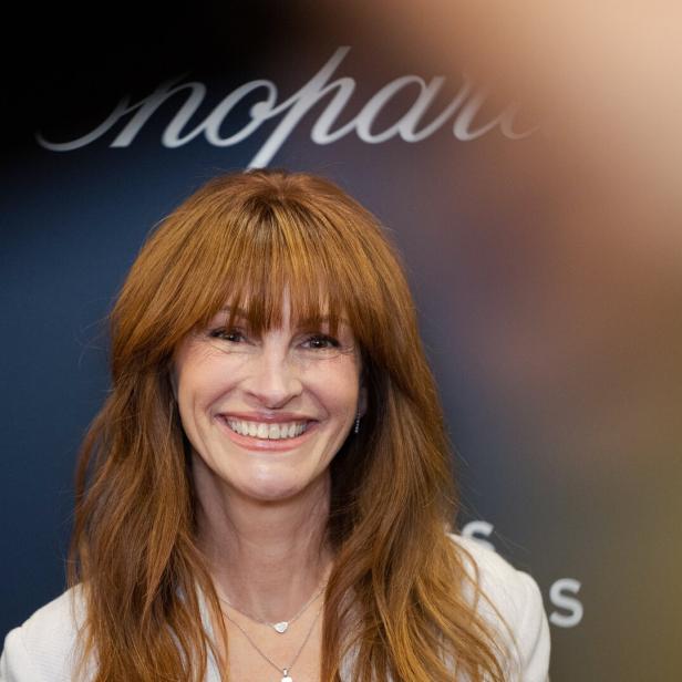 Julia Roberts lächelt vor einem Hintergrund mit dem Schriftzug „Chopard“.