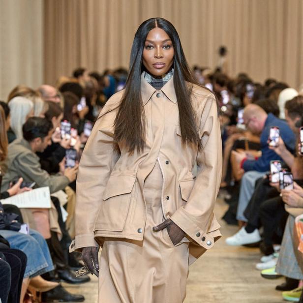 Naomi Campbell läuft in einem beigen Hosenanzug über einen Laufsteg.