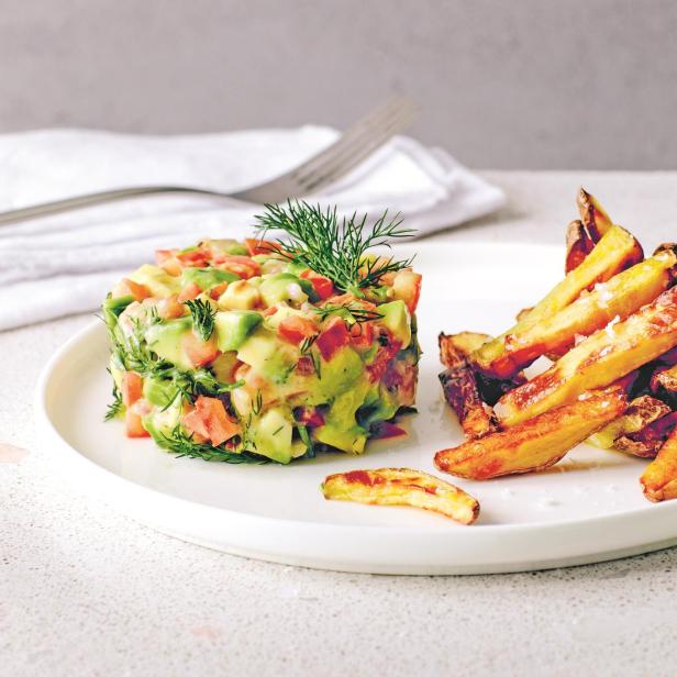 Ein Avocado-Tatar mit Tomaten und Dill wird mit Pommes Frites serviert.
