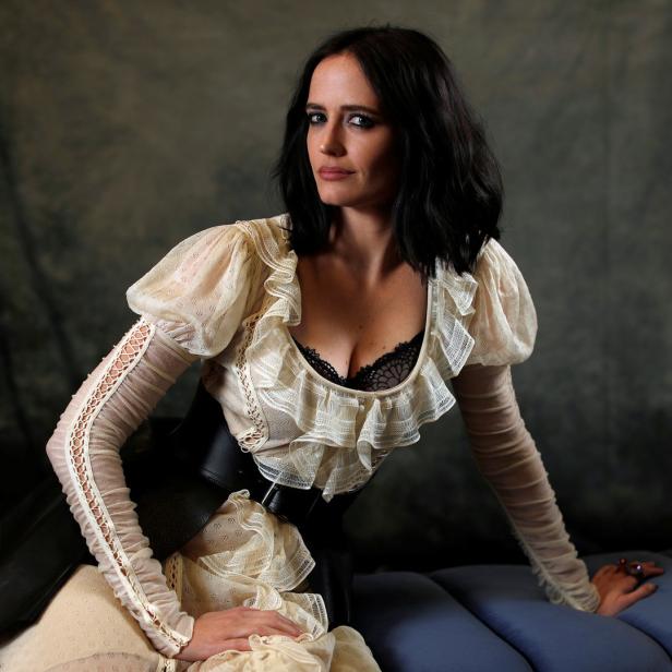 Eva Green posiert in einem elfenbeinfarbenen Kleid mit Rüschen und einem breiten Gürtel.