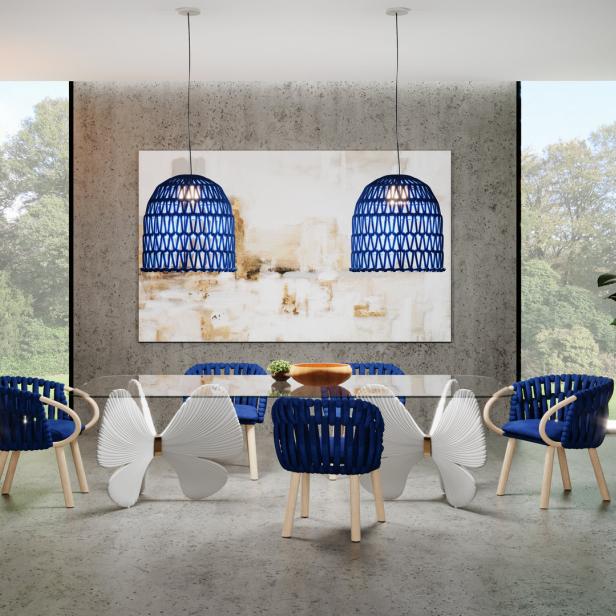 Ein Esszimmer mit einem gläsernen Tisch und blauen Stühlen unter zwei blauen Hängelampen.