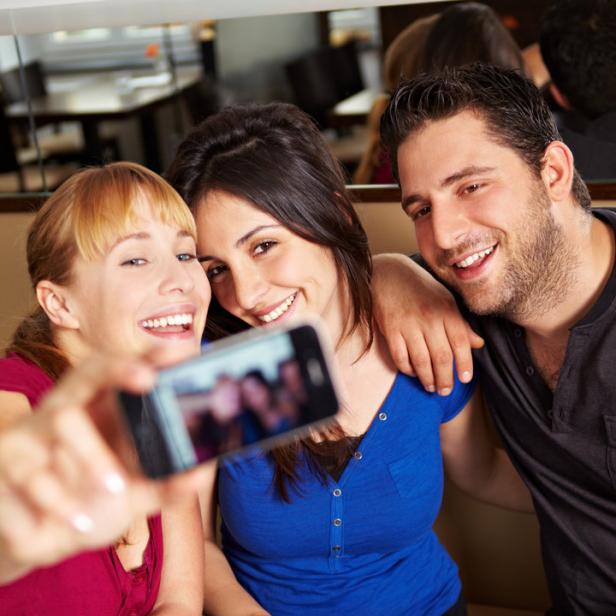 Drei Freunde machen ein Selfie in einem Café.
