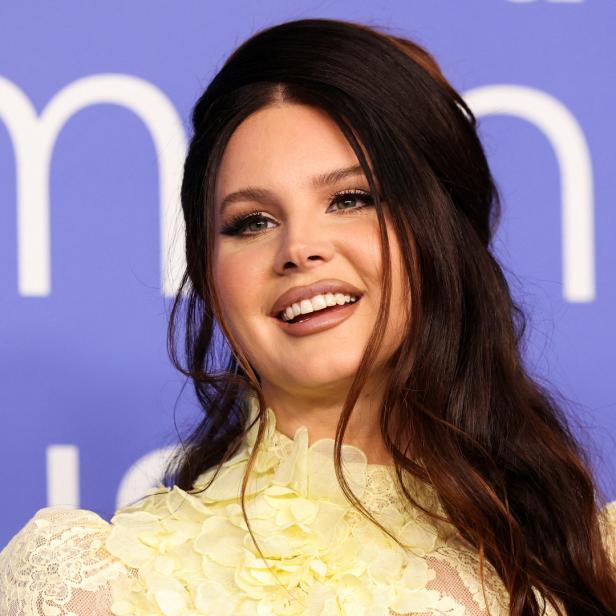 Lana Del Rey lächelt in einem gelben Kleid.