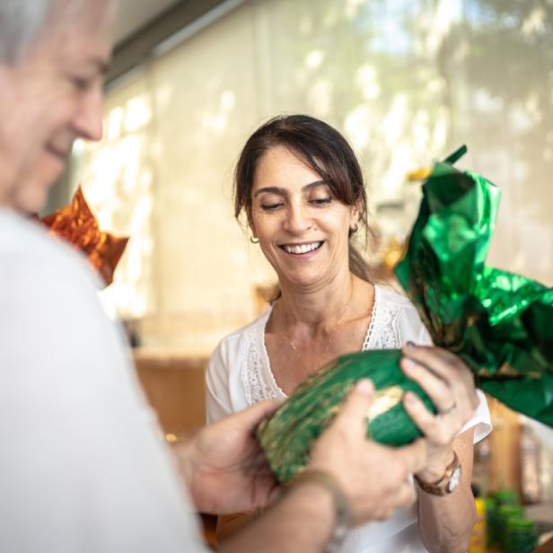 Eine Frau nimmt von einem Mann ein in grünes Papier verpacktes Geschenk entgegen.