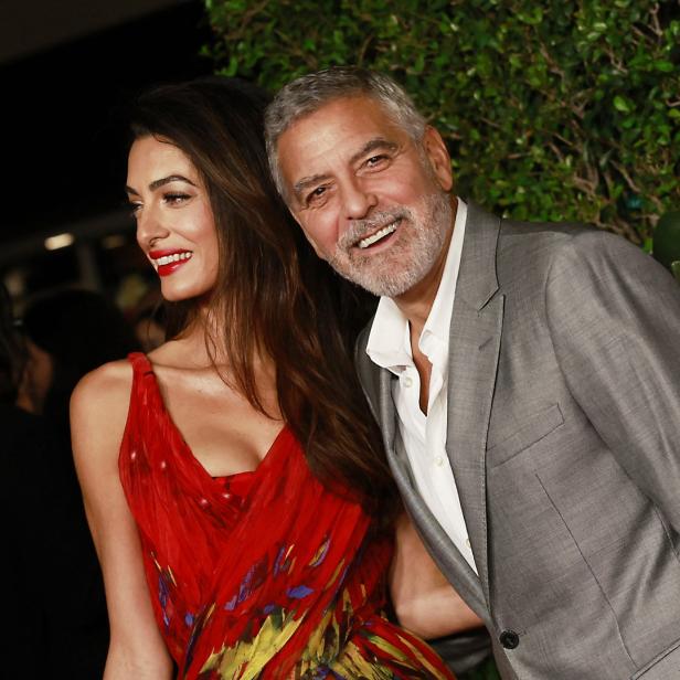 Amal und George Clooney posieren auf dem roten Teppich.