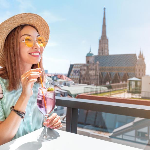 Eine Frau genießt einen Drink mit Blick auf den Stephansdom in Wien.