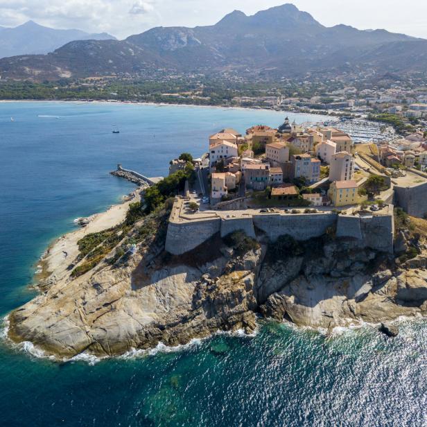 Luftaufnahme von Calvi, einer Stadt auf Korsika, mit Blick auf das Meer und die Berge.