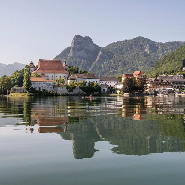 Das Stift St. Wolfgang am Wolfgangsee spiegelt sich im Wasser.