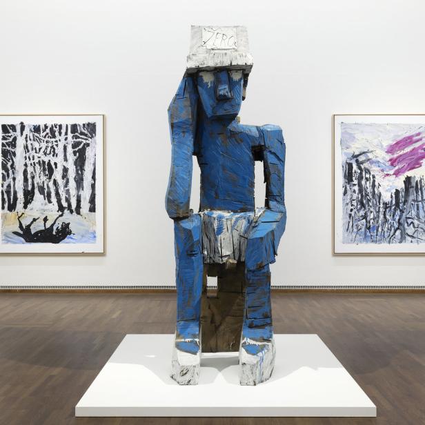 Eine blaue Holzskulptur mit der Aufschrift „Zero“ auf dem Kopf in einer Kunstgalerie.