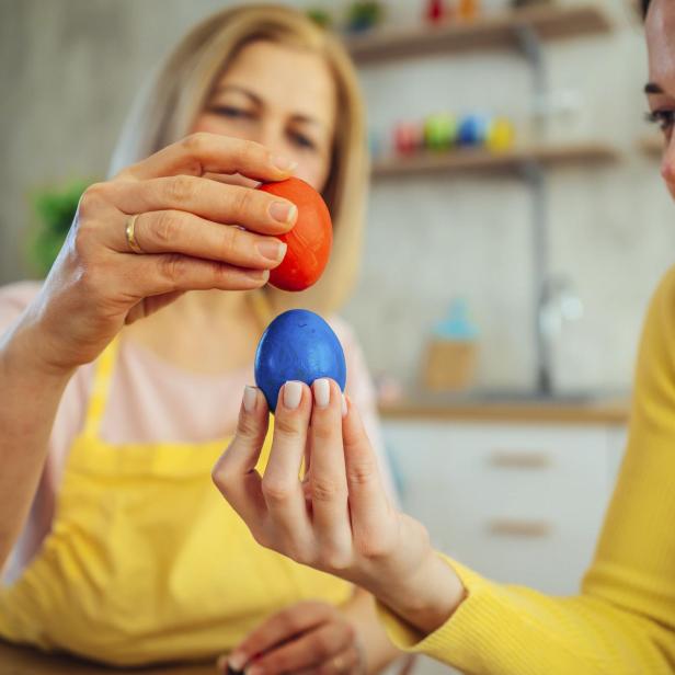 Zwei Frauen bemalen Ostereier in einer Küche.