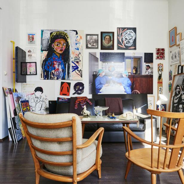 Ein Wohnzimmer mit Kunstwerken an der Wand und zwei Sesseln im Vordergrund.