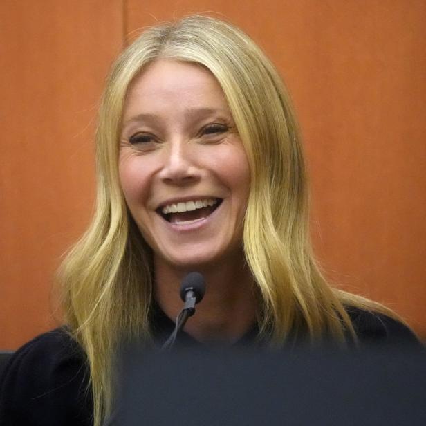 Gwyneth Paltrow lächelt vor einem orangefarbenen Hintergrund.