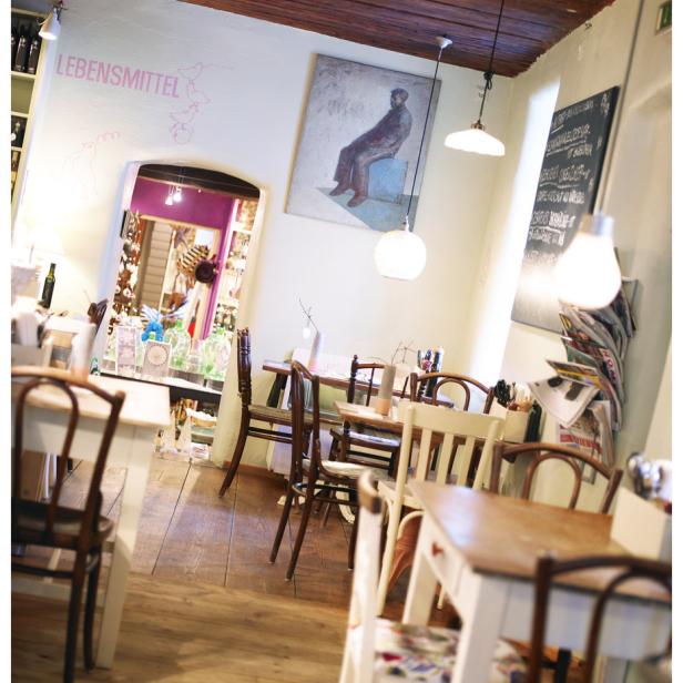 Einladendes Interieur eines kleinen Restaurants mit Holztischen und Stühlen.