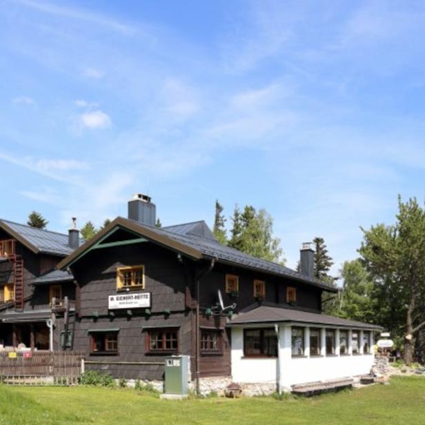 Die W. Eichinger-Hütte liegt auf einer grünen Wiese unter blauem Himmel.