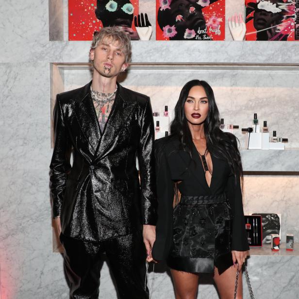 Machine Gun Kelly und Megan Fox posieren zusammen vor einer Marmorwand mit Kunst und Produkten.