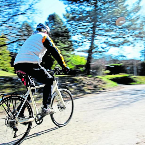 Eine Person fährt mit einem E-Bike auf einer Landstraße.