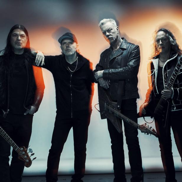 Die Band Metallica posiert mit ihren Instrumenten vor einem weißen Hintergrund.