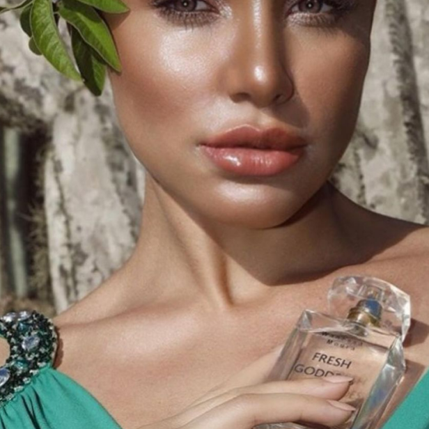 Eine Frau mit glänzender Haut hält ein Parfüm namens „Fresh Goddess“.