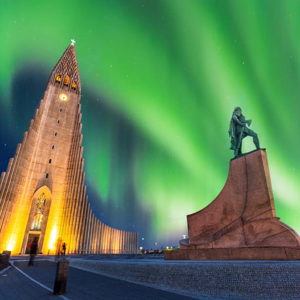 Die Hallgrímskirkja-Kirche und eine Statue in Reykjavik unter dem Nordlicht.