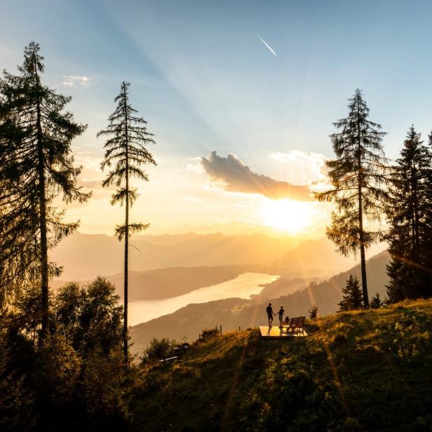 Ein Paar genießt den Sonnenuntergang mit Blick auf einen See und die Berge.