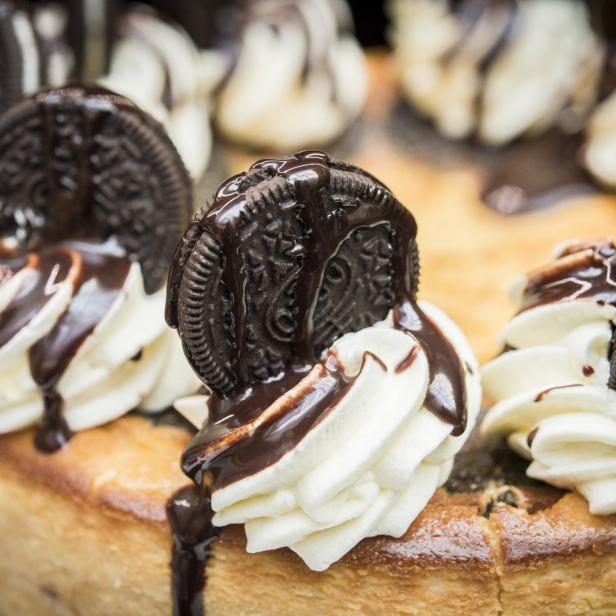 Ein Käsekuchen ist mit Schlagsahne, Schokoladensoße und Oreo-Keksen garniert.