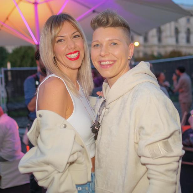 Zwei Frauen lächeln bei der MQ Vienna Fashion Week in die Kamera.