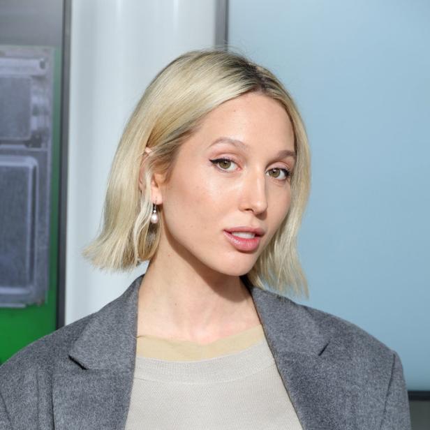 Eine Frau mit blonden Haaren und einem grauen Blazer blickt in die Kamera.