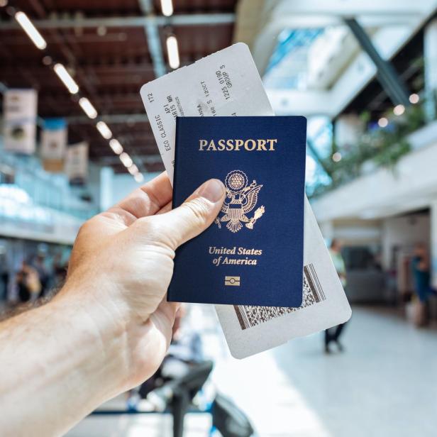 Eine Hand hält einen Reisepass der Vereinigten Staaten und eine Bordkarte.